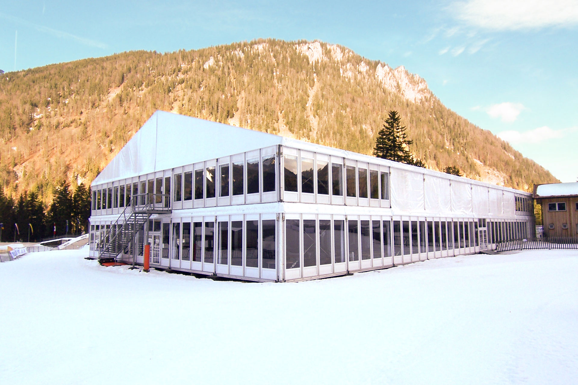 Mehrstöckiges weißes Zelt im Schnee mit Glasfassade