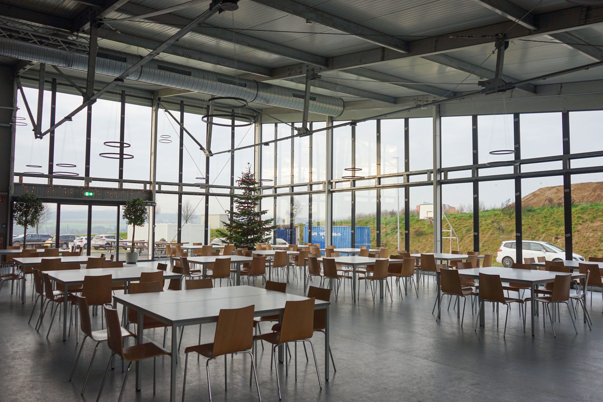 Lichtdurchflutete Mensa mit großer Fensterfront in einer Interimslösung Schule