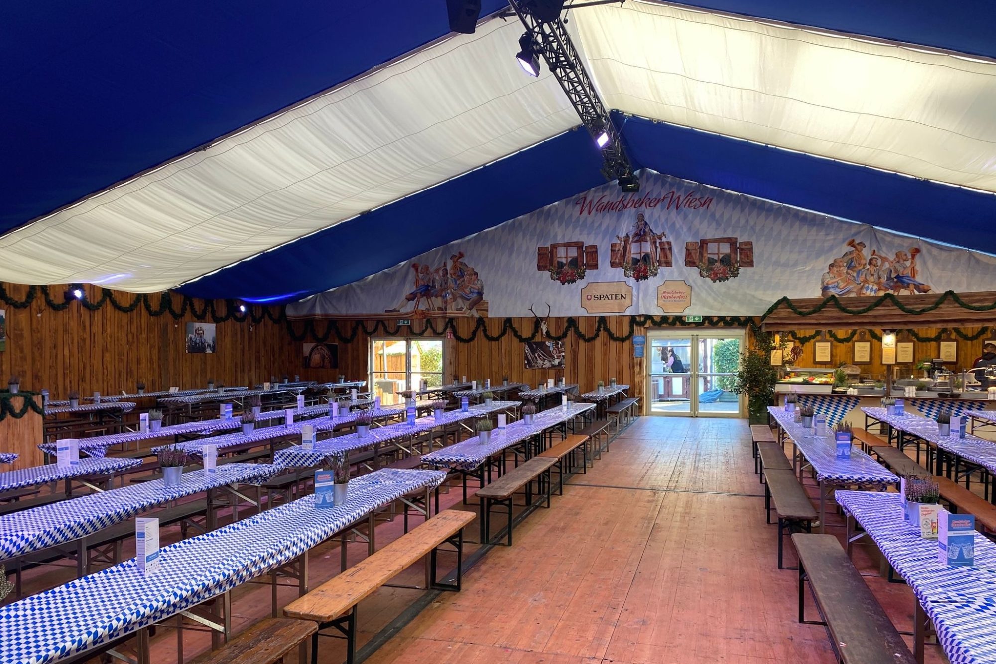 Gemütliche Atmosphäre im Oktoberfest-Zelt mit Holzwänden, Festbeleuchtung und langen Sitzbänken – perfekt für Feiern, Musik und bayerische Stimmung.